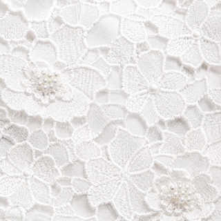 Detailaufnahme Blumenapplikationen mit Perlen auf weißem Spitzen Top – Materialdetail