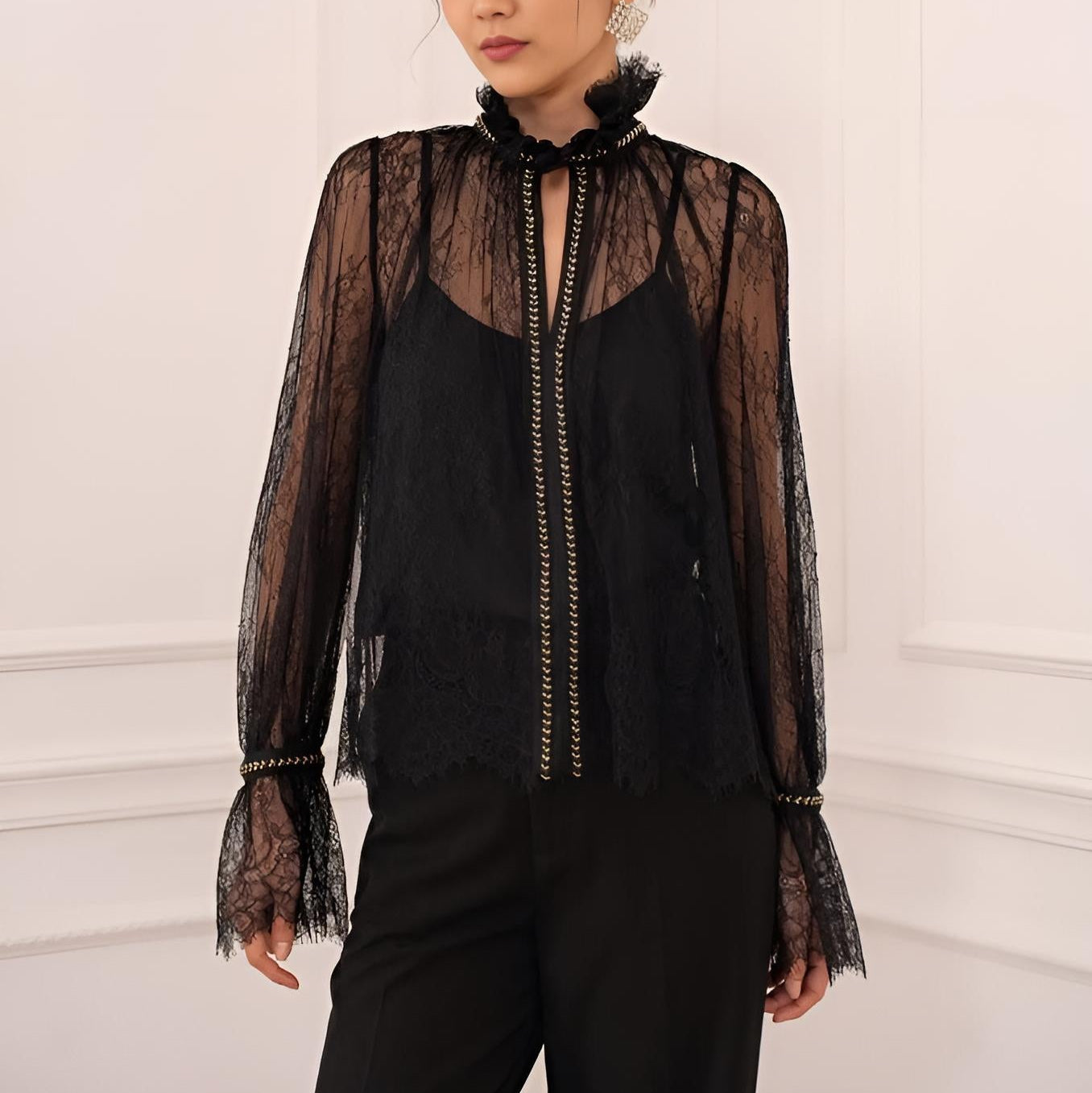Vordere Ansicht einer schwarzen transparenten Spitzenbluse mit Rüschenkragen und silbernen Akzenten