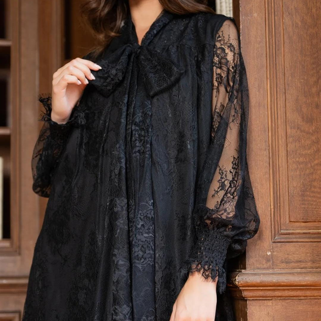 Detailaufnahme des schwarzen Spitzenkleids mit Schleife und transparenter Spitze