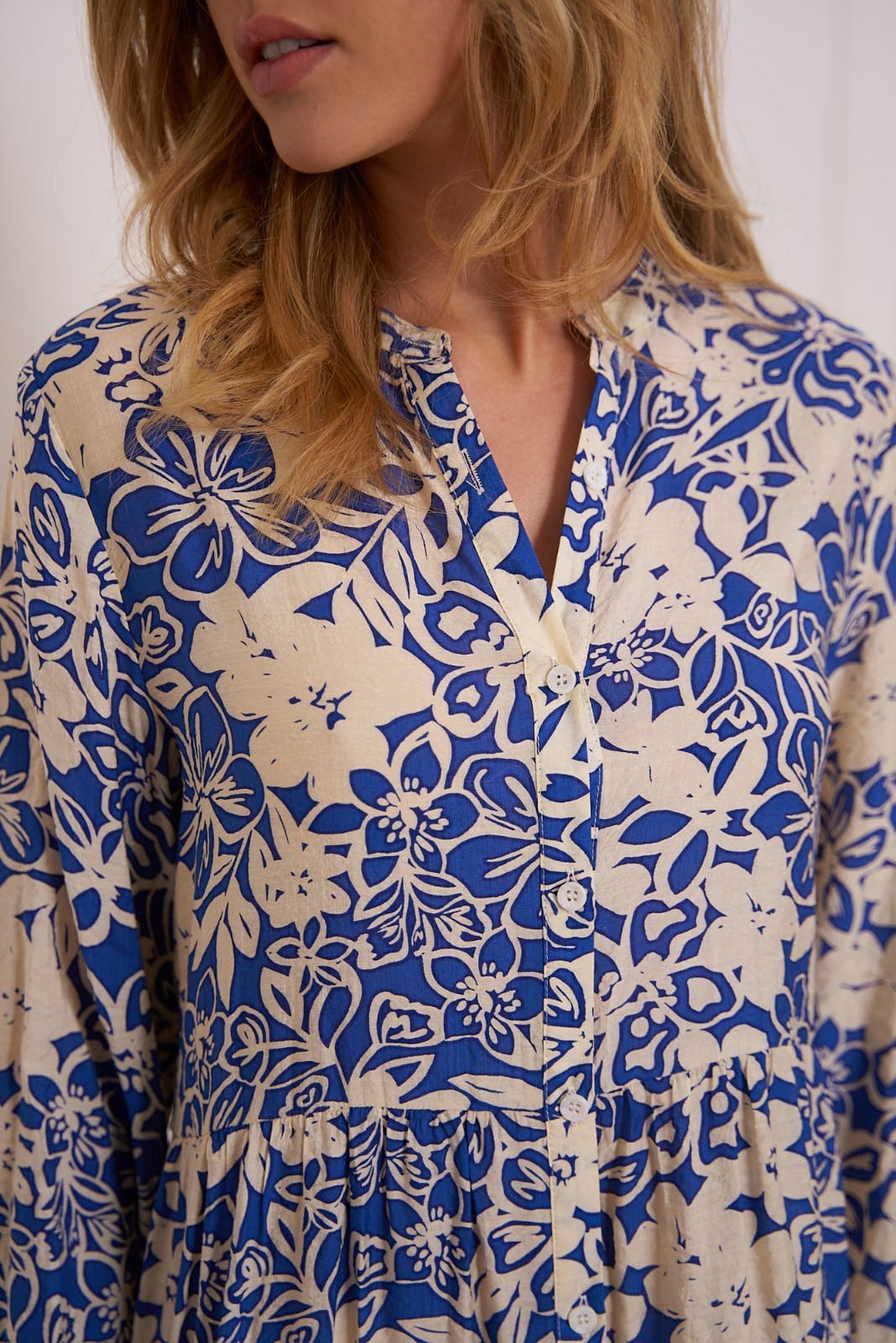 Detailansicht des beige-blauen Maxikleids mit floralem Muster und Knopfleiste am Oberteil.