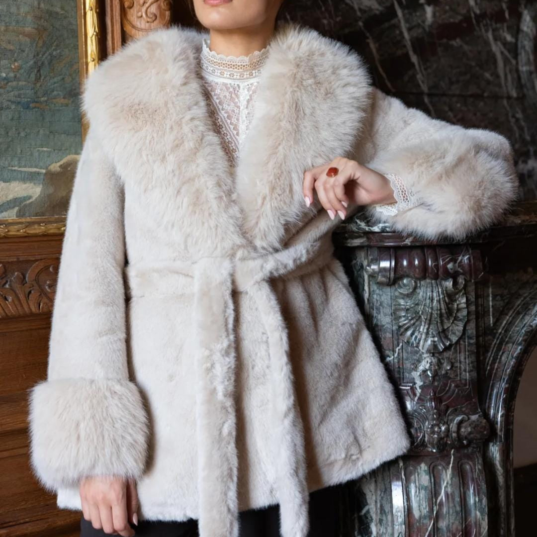 Damen Kunstfelljacke cremefarben mit Bindegürtel und weitem Kragen, getragen von Model im eleganten Interieur